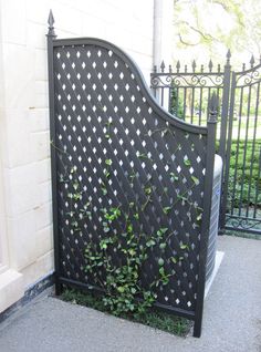 an iron gate with ivy growing on it in front of a brick wall and wrought iron fence