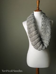 a white mannequin with a gray knitted scarf on it's neck