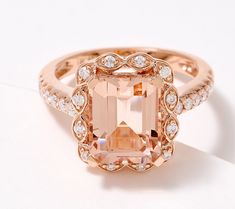 a fancy ring with an orange diamond surrounded by white diamonds on a white table top