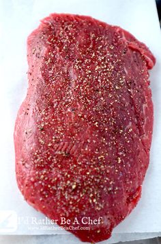 raw ground beef sitting on top of a piece of paper with seasoning sprinkles