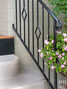 a planter with pink flowers sitting on the steps next to a brick wall and metal handrail