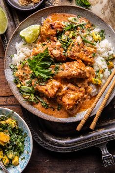 a bowl filled with chicken and rice next to chopsticks on top of a table