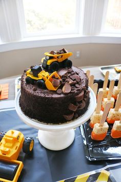 there is a chocolate cake with toy trucks on it