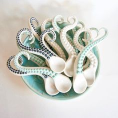 an octopus sculpture is sitting in a bowl on the table next to some spoons