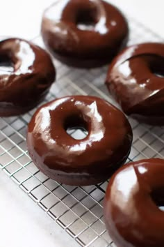 six chocolate donuts on a cooling rack ready to be eaten by the owner or cook