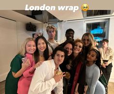 a group of people posing for a photo in front of a wall with the words london wrap on it