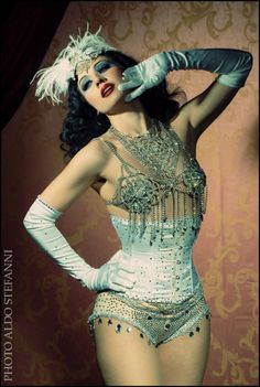 a woman in a white and silver costume with gloves on her head is posing for the camera