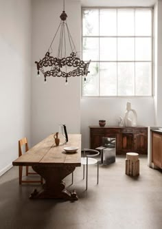 a dining room table and chairs in front of a window with a chandelier