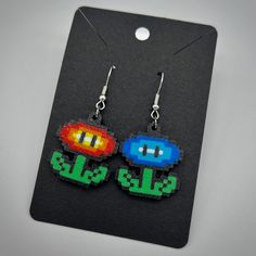 These cute and colorful pixel-style Mario flower earrings are 3d printed in PLA plastic, with stainless steal nickel-free hooks attached. Each side is around the size of a quarter (see second photo for a comparison). Thanks for looking! Perler Bead Flower Earrings, Pixel Bead Earrings, Mario Flower, Mario Fire Flower Perler Beads, Gamer Earrings, Flower Bead Earrings, Nintendo Earrings, Laser Cut Earrings Acrylics, Pixel Heart