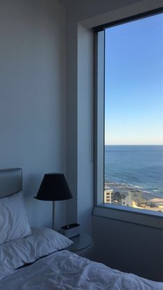 a bedroom with a large window overlooking the ocean