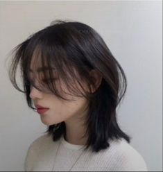 a woman with long black hair is wearing a white sweater and has her eyes closed