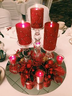 red candles are sitting on a table with silver plates and white clothed tablescloths