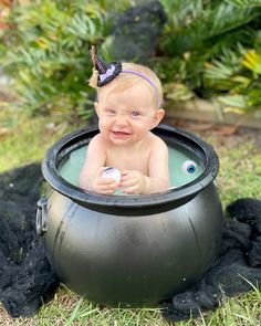 a baby sitting in a metal pot on the ground