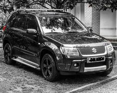 a black and white photo of a car parked in front of a building with trees