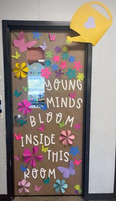 a classroom door decorated with flowers and a yellow watering hat that says young minds bloom inside this room