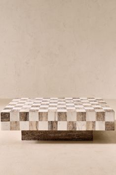 a white and black checkered coffee table sitting on top of a wooden stand in front of a wall