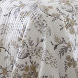 the comforter is made up with white and gold flowers on it, along with matching pillows