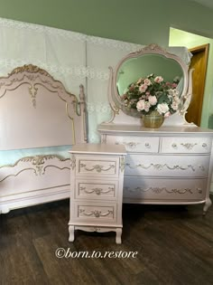 a white dresser sitting next to a bed and a mirror on top of a wooden floor