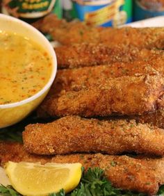 fried fish sticks with lemon and parsley garnish on a white platter