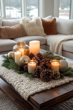 candles and pine cones are arranged on a coffee table