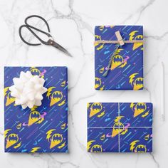 wrapping paper and scissors on a marble countertop with blue wrapping paper, yellow wrapping paper, and white tissue