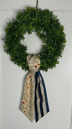 a wreath hanging on the wall with two ties tied to it's sides and an american flag