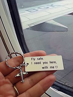 a person holding a keychain that says fly safe i need you here with me