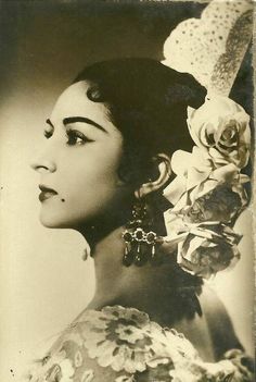 an old black and white photo of a woman with flowers in her hair wearing earrings