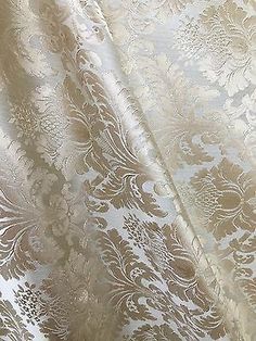 a close up view of a white and gold brocaded fabric with an intricate design