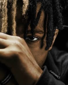 a close up of a person with dreadlocks covering his face and looking at the camera