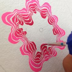 someone is using a marker to draw a pink and white flower design on a piece of paper