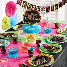 a birthday party table set up with plates, cups and napkins