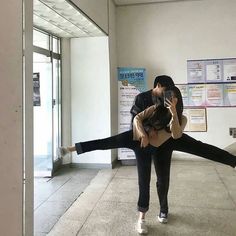 two people are dancing together in an empty room with posters on the wall behind them