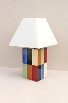 a lamp that is sitting on top of a white tablecloth with multicolored squares