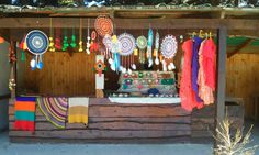 an outdoor market with lots of colorful items hanging from it's roof and decorations on the outside