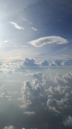 the view from an airplane window shows clouds and blue sky in the distance with sun shining through