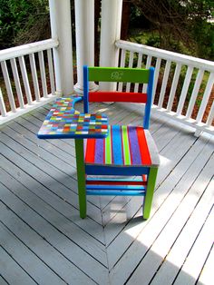 a colorful wooden chair sitting on top of a white porch next to a table and chairs