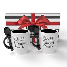 two coffee mugs in front of a gift box with a red bow on it