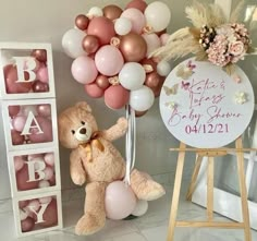 a teddy bear sitting next to a sign and balloons