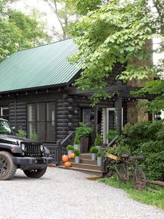 a black jeep parked in front of a log cabin with a green roof and door