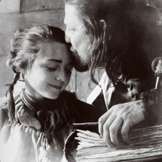 an old black and white photo of a man kissing a woman's forehead as she looks at papers