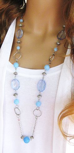 a woman wearing a necklace with blue beads and silver chains on it's neck