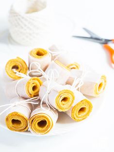 rolls of rolled up paper on a white plate with scissors and yarn in the background