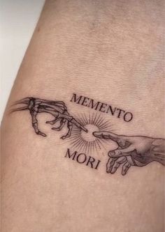 a tattoo that says mementoo mori with two hands reaching for each other