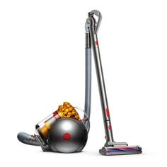 a silver and red vacuum is next to a gray ball with popcorn on the floor