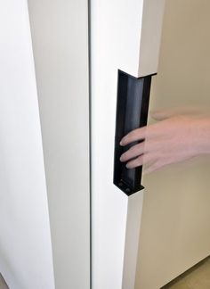 a person's hand is holding the door handle on a white refrigerator