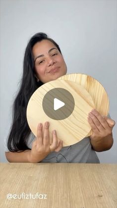 a woman holding up a wooden object with the video below it