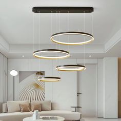 a modern living room with white furniture and round lights hanging from the ceiling above it