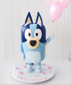 a blue and white cake with a cartoon character holding two pink balloons in it's hand