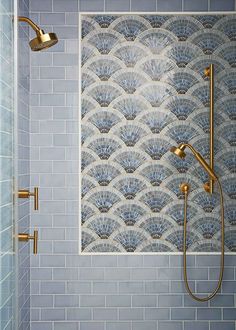 a bathroom with blue tile and gold faucet shower head, hand held showerhead, and tiled walls